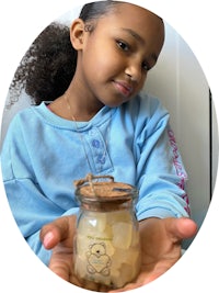 a little girl holding up a jar of honey