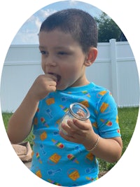 a young boy eating a jar of peanut butter